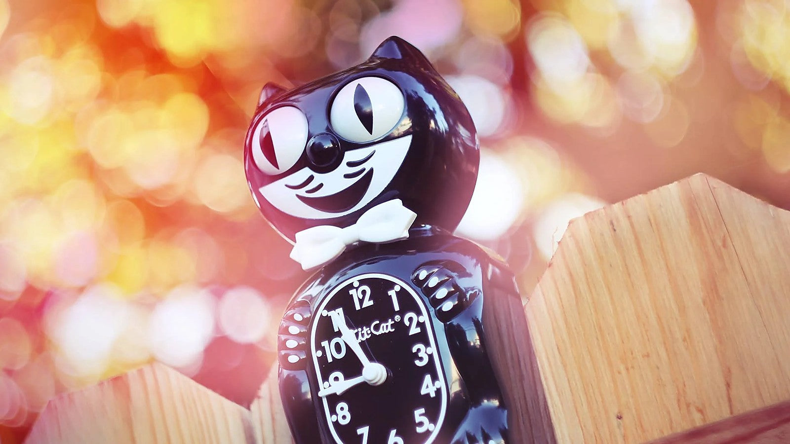 Kit-Cat Clock Katzen-Wanduhr mit Bokeh-Hintergrund – Dekoration bei Chat Noir Bern
